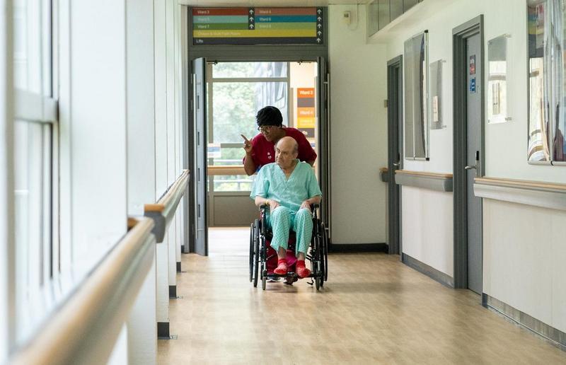 NHS staff wheeling a patient down corridor